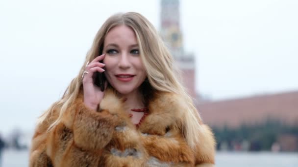 Aantrekkelijke gelukkig glamoureuze vrouw in vos bontjas praten aan de telefoon, buitenshuis — Stockvideo