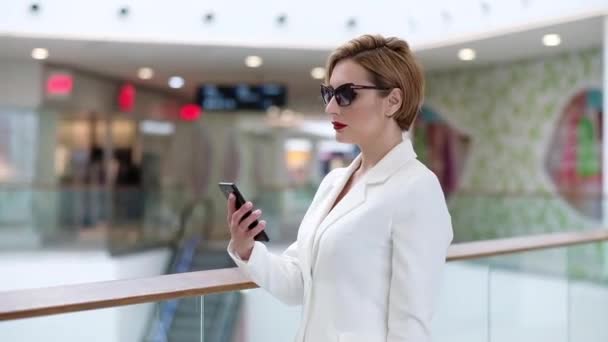 Atrakcyjny biznes czarujący dama w białym garniturze rozmawiać przez telefon, w pomieszczeniu — Wideo stockowe