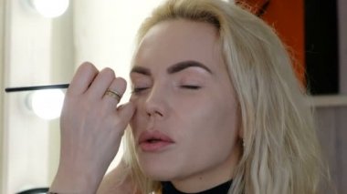 Profesyonel makyöz güzel genç bir kadınla çalışıyor.