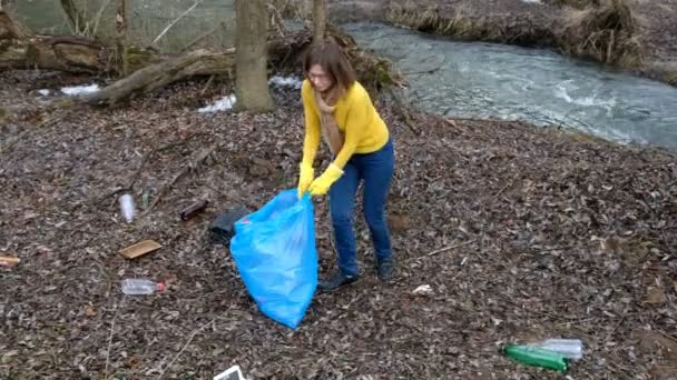 Kadın gönüllüsü nehir kenarında çöpü temizliyor. Açık havada çöp toplamaya. Ekoloji ve çevre konsepti — Stok video