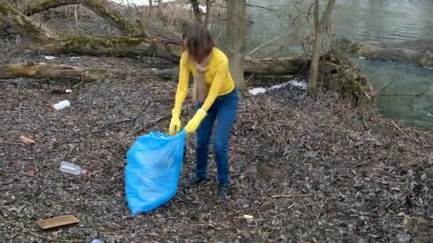 Kvinna volontär städa upp pappers korgen vid floden. Plocka upp sopor utomhus. Ekologi och miljö koncept — Stockvideo