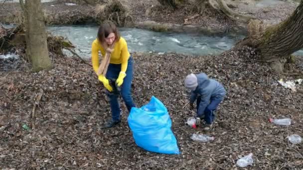 Eine Frau räumt mit ihrem Kind freiwillig den Müll am Fluss auf. Ökologie und Umweltkonzept — Stockvideo