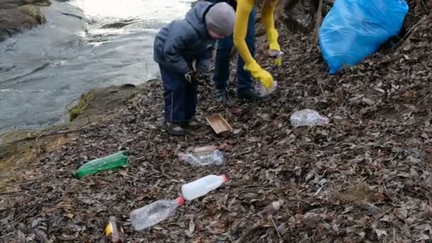 Mulher voluntária com o filho a limpar o lixo junto ao rio. Conceito de ecologia e ambiente — Vídeo de Stock