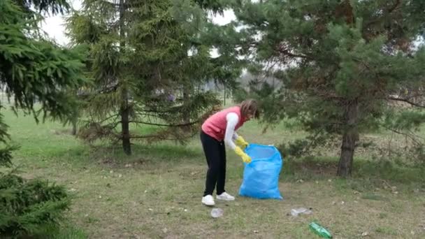 Mulher voluntária a limpar o lixo no parque. A apanhar lixo plástico ao ar livre. Conceito de ecologia e ambiente — Vídeo de Stock