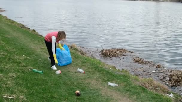 Vrouw vrijwilliger schoonmaken van de Prullenbak door de rivier. Het oppakken van vuilnis buitenshuis. Ecologie en milieu concept — Stockvideo