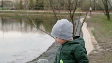 Nehir tarafından kabarcıklar ile küçük sevimli çocuk, açık havada