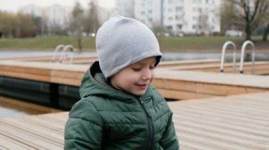 Küçük çocuk nehir kıyısında açık havada oturuyor, öksürüyor.