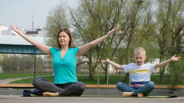 Femme avec son fils faisant du yoga au bord de l'étang, à l'extérieur — Video