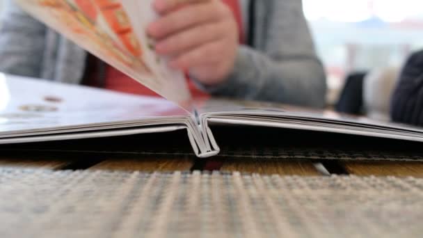 Gros plan de doigt d'homme avec menu choisir des plats au restaurant — Video