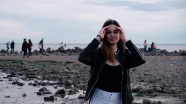 Deniz kenarında koyu saçlı güzel genç kız. Gün batımı ışığı. Yavaş çekim