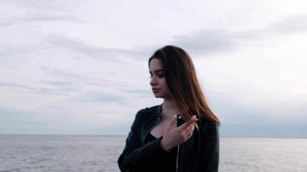 Belle jeune fille aux cheveux foncés au bord de la mer. Lumière du coucher du soleil. Mouvement lent — Video