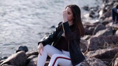 Deniz kenarında koyu saçlı güzel genç kız. Gün batımı ışığı. Yavaş çekim