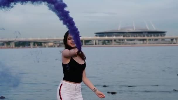 Belle jeune fille sexy et élégante au bord de la mer tenir une lumière bombes de fumée de couleur. Mouvement lent — Video