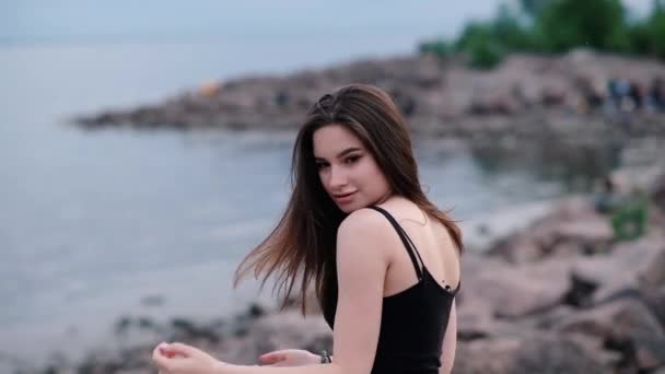 Mooi jong meisje met donker haar aan de kust. Zonsondergang licht. Slow Motion — Stockvideo