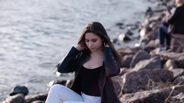 Menina bonita com cabelo escuro à beira-mar. Luz do pôr-do-sol. Movimento lento — Vídeo de Stock