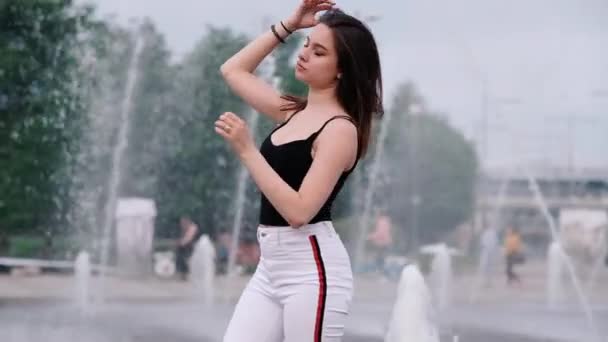 Krásná mladá dívka s tmavými vlasy u fontány. Zpomaleně — Stock video