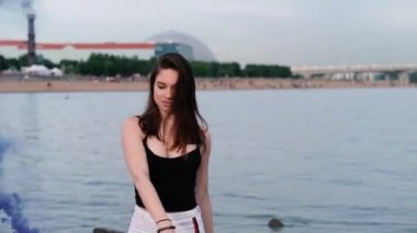 Deniz kenarında güzel mutlu şık seksi genç kız renkli sis bombaları kadar bir ışık tutun. Yavaş çekim