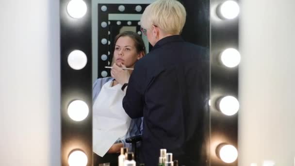 Professionele make-up kunstenaar werken met mooie jonge vrouw — Stockvideo