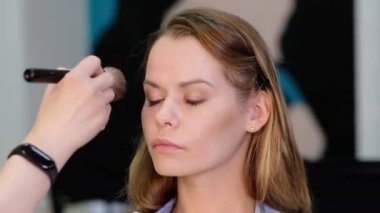 Profesyonel makyöz güzel genç bir kadınla çalışıyor.