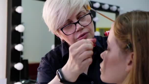 Professionell makeup artist arbetar med vacker ung kvinna — Stockvideo