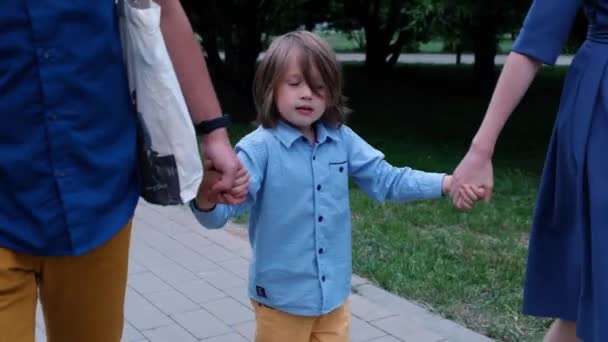 Gelukkige kleine jongen lopen en houden van zijn ouders handen, close-up — Stockvideo