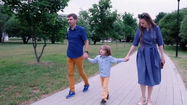 Happy familjekoncept: mor, far och liten pojke som går i parken. Sommar utomhus — Stockvideo