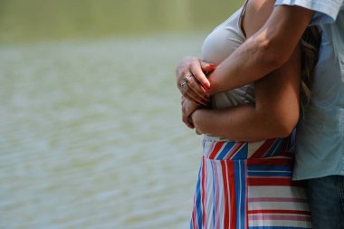 Genç sevgi dolu çift, nehir tarafından güzel bir yerde şefkatle birbirlerine kucaklayan. Yakın çekim