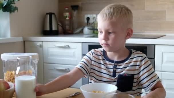 Cute Boy 4 lat po śniadaniu płatki kukurydziane z mlekiem przy stole w domu. — Wideo stockowe