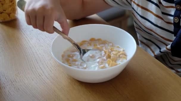 Sevimli çocuk 4 yaşında evde masada süt ile kahvaltı mısır gevreği olan. — Stok video