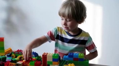 Sevimli çocuk evde masada renkli plastik oyuncak tuğla ile oynarken 4 yaşında.