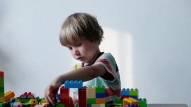 Sevimli çocuk evde masada renkli plastik oyuncak tuğla ile oynarken 4 yaşında.