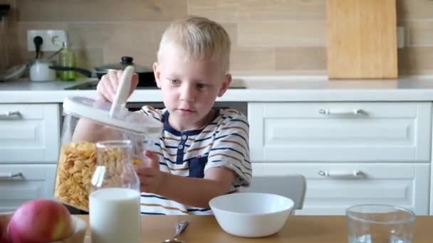 Söt pojke 4 år gammal med frukost cornflakes med mjölk vid bordet hemma. — Stockvideo