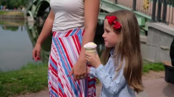 Ragazzina che mangia un gelato, che tiene per mano le madri. Estate all'aria aperta — Video Stock