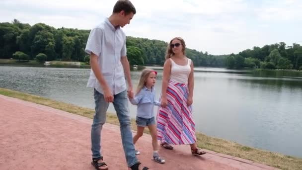 Концепция семьи: женщина, мужчина и дочь гуляют в парке. Лето на природе — стоковое видео