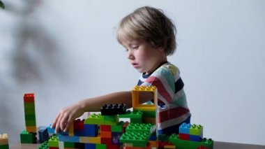 Sevimli çocuk evde masada renkli plastik oyuncak tuğla ile oynarken 4 yaşında.