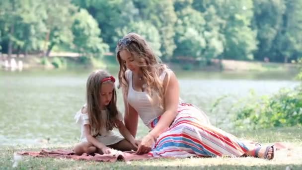 娘と一緒に公園に座り、子供とコミュニケーションをとる女性。ファミリーコンセプト — ストック動画