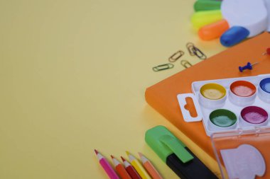 Geri okul kavramı, sarı arka plan üzerinde çeşitli okul malzemeleri ve kırtasiye ile yaratıcı düzeni.