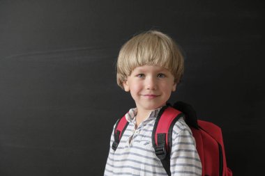 Okula geri dön. Tahtadaki sevimli çocuk. İlkokuldan çantalı çocuk. Eğitim kavramı.