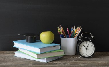 Geri okul konsepti, okul malzemeleri, elma ve kırtasiye siyah tahta ahşap masada