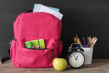 Geri okul konsepti, okul malzemeleri, çanta ve siyah tahta ahşap masa üzerinde kırtasiye
