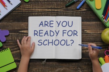 Okul konsepti için hazır, ahşap masa üzerinde çeşitli okul malzemeleri ve kırtasiye ile yaratıcı düzeni. Çocuk elleri. Düz döşeme stil kompozisyonu, yukarıdan görünüm