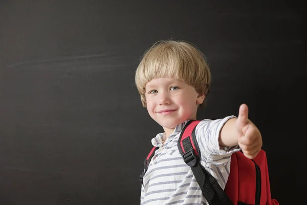 학교로 돌아갑니다. 칠판에서 귀여운 작은 소년입니다. 초등학교 어린이의 가방첨부. 교육 개념. — 스톡 사진