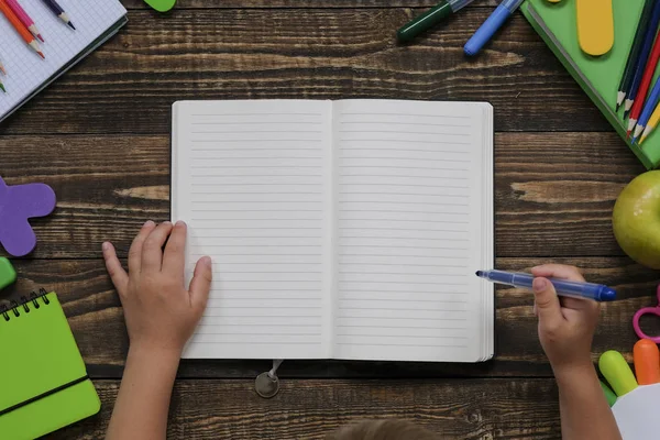 Geri okul konsepti, ahşap masa üzerinde çeşitli okul malzemeleri ve kırtasiye ile yaratıcı düzeni. Çocuk elleri. Düz döşeme stil kompozisyonu, yukarıdan görünüm