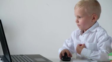 Sevimli küçük çocuk masada oturan ve oyun ya da bir bilgisayar üzerinde çalışıyor. İlkokuldan bir çocuk. Eğitim kavramı. Okula geri dön.