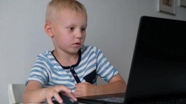 Sevimli küçük çocuk masada oturan ve oyun ya da bir bilgisayar üzerinde çalışıyor. İlkokuldan bir çocuk. Eğitim kavramı. Okula geri dön.