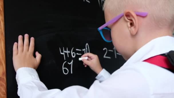 Schattige kleine jongen schrijven op Blackboard. Kind van basisschool met tas. Onderwijsconcept. Terug naar school. — Stockvideo