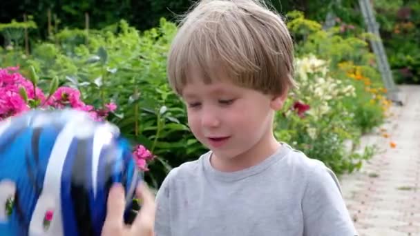 엄마는 아들이 도시 공원에서 자전거를 안전하게 타기 위해 헬멧을 착용하는 것을 돕습니다. — 비디오