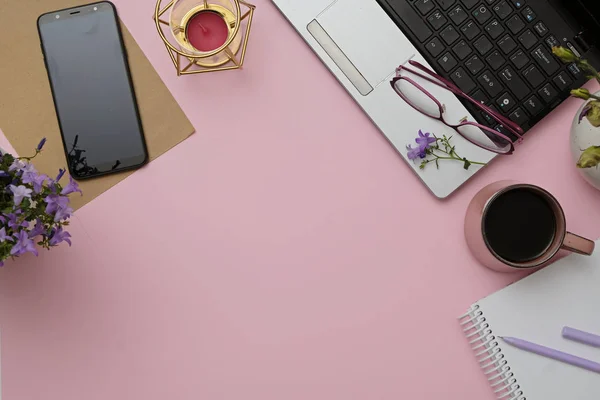 Flat lay modern workspace pink desk with laptop, glasses, smartphone, coffee cup. Business lady blog hero concept.