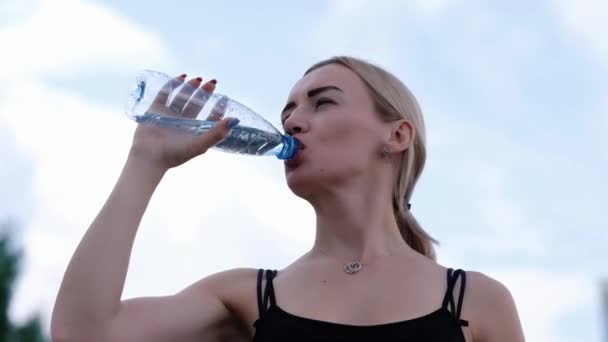 Giovane donna sportiva che beve acqua naturale da una bottiglia. Fitness e stile di vita concetto — Video Stock