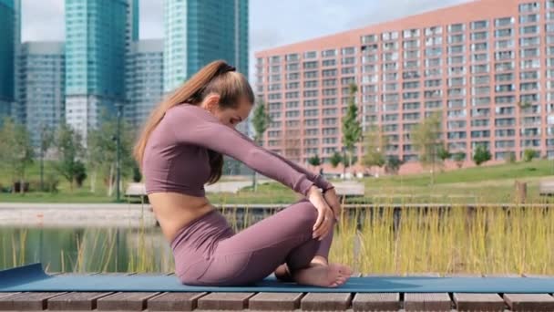 背景に都市とヨガの練習をしている若い女性。リラックスと自由の概念. — ストック動画